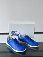 Blue lace-up sneakers with white soles, front view pair on a box