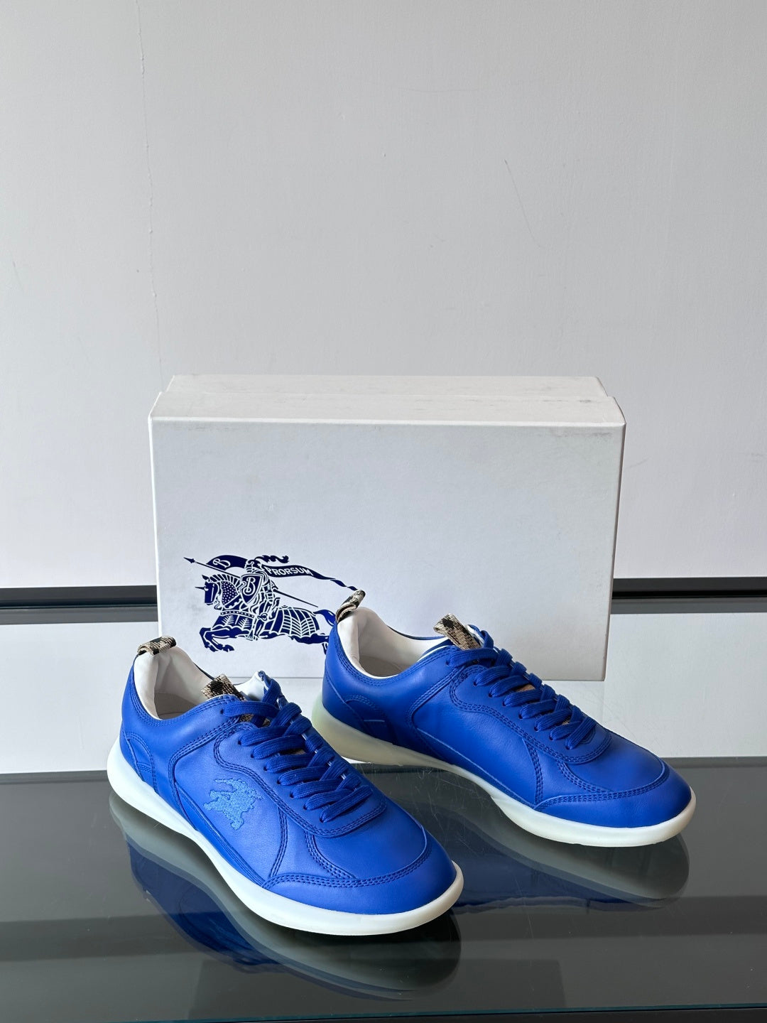 Blue lace-up sneakers with white soles, front view pair on a box