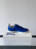 Blue lace-up sneaker on a box, front-left angle with white sole
