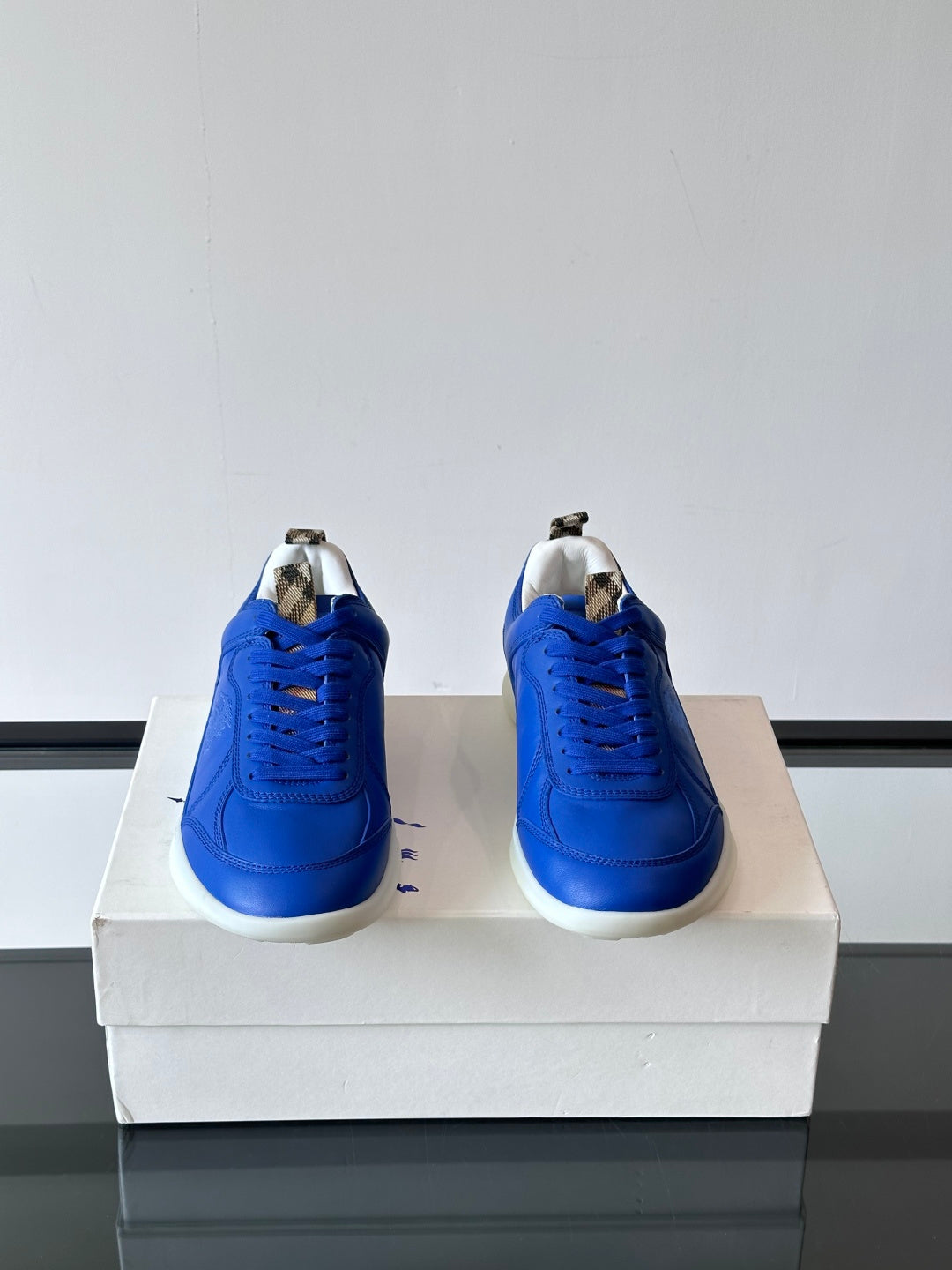 Blue lace-up sneakers with white soles, back view showing heels on a box