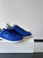 Blue lace-up sneakers with white soles, close side view of two shoes