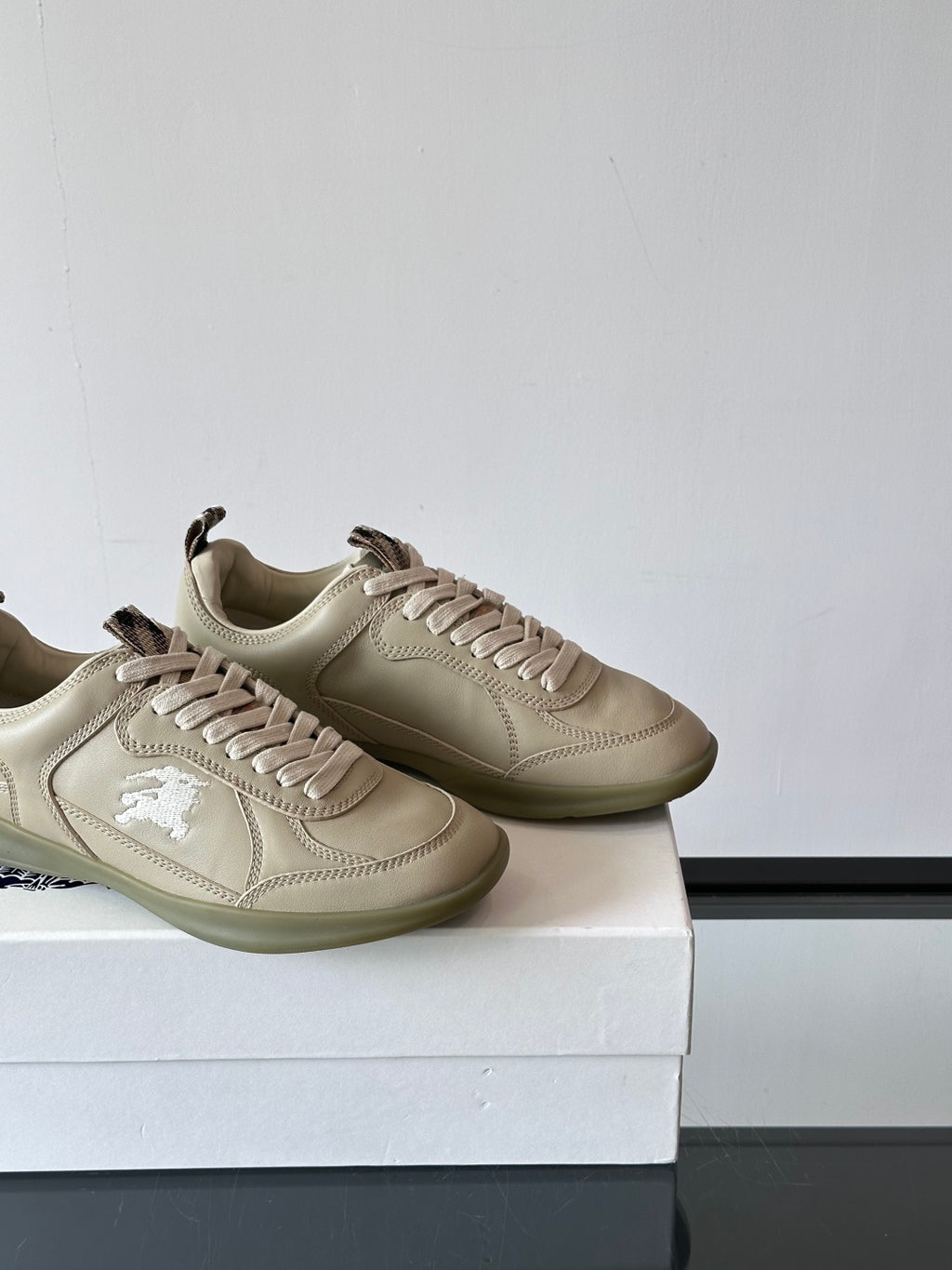 Burberry cream lace-up sneakers, two pairs side by side on box, logo at side