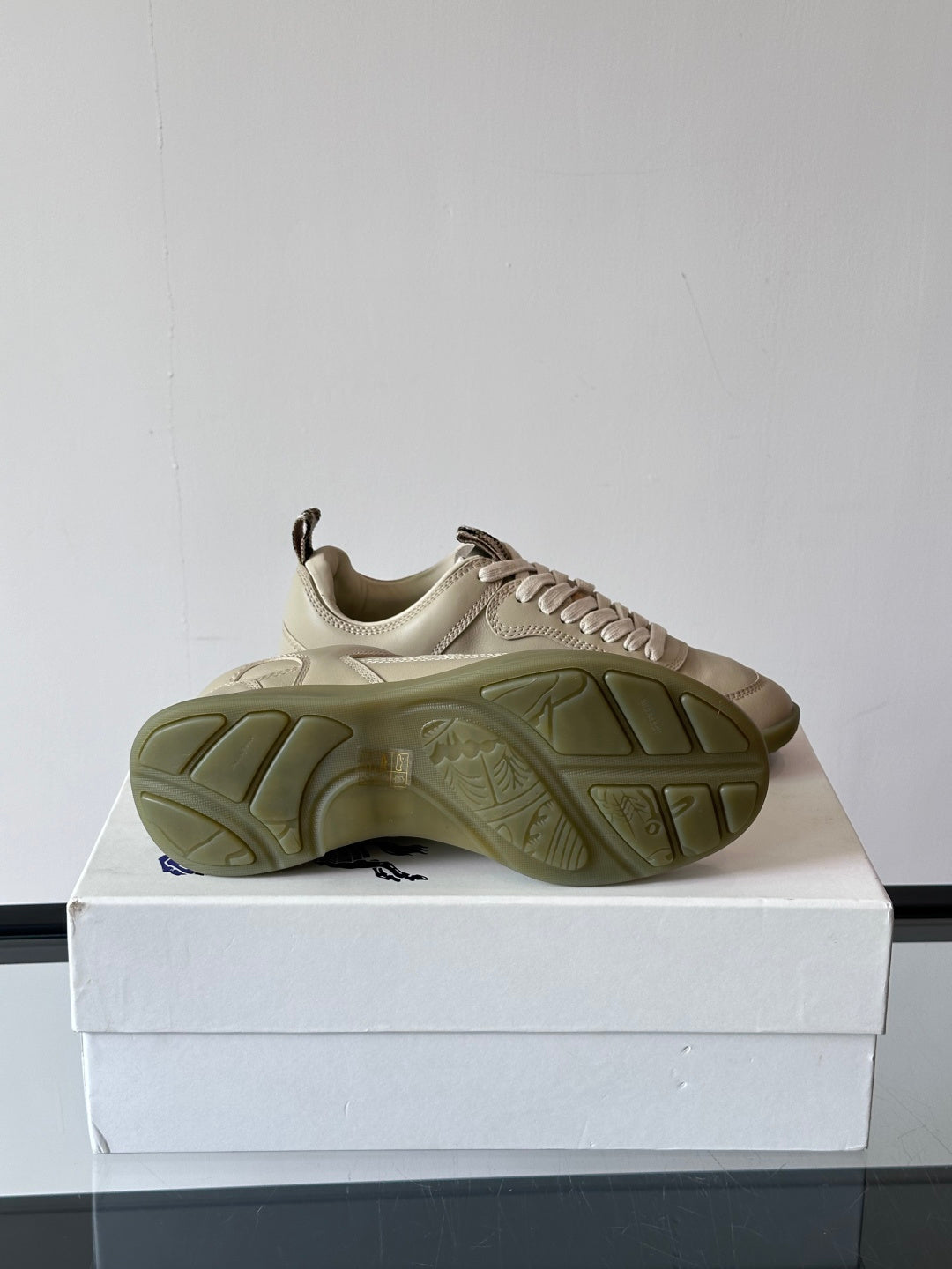 Burberry sneaker outsole view, cream upper with ridged rubber tread