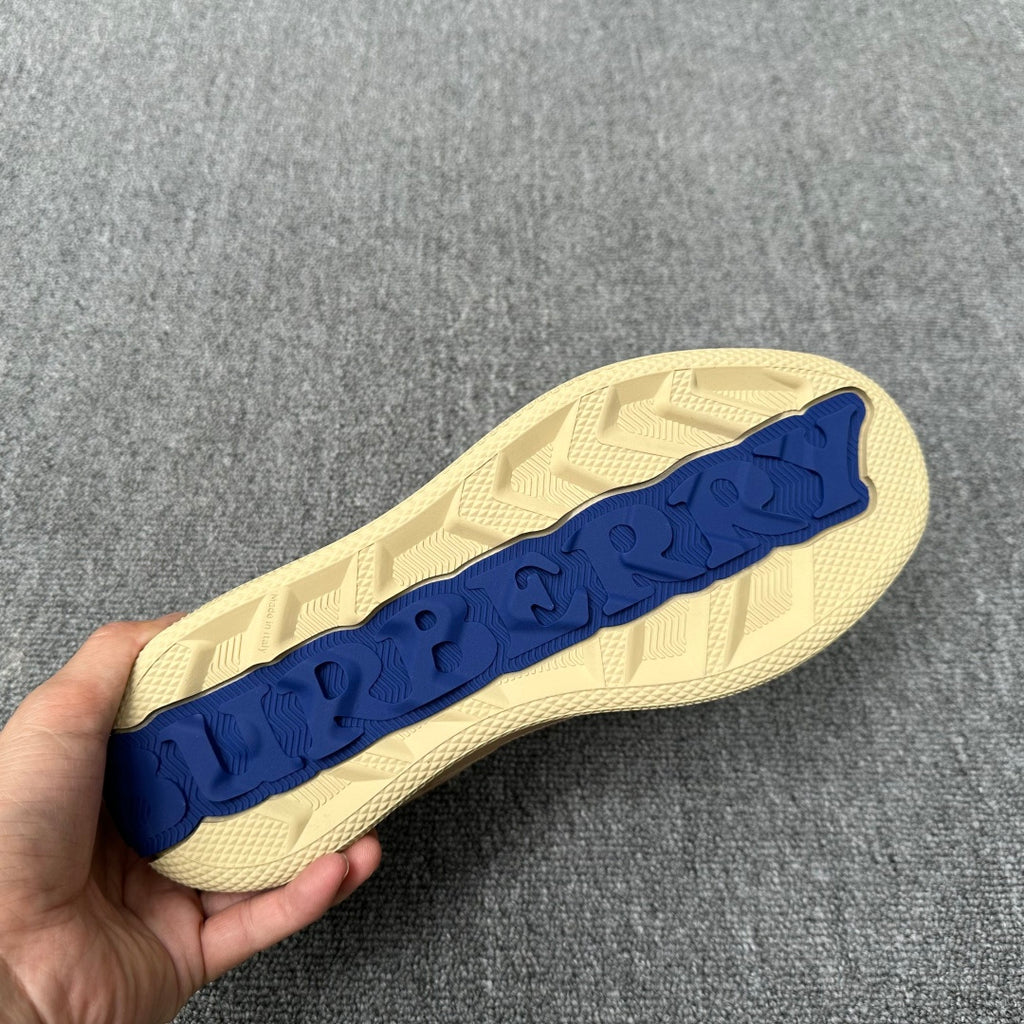 Beige sneaker outsole with raised pattern and blue logo strip