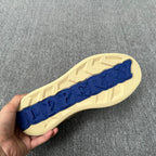 Beige sneaker outsole with raised pattern and blue logo strip