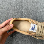 Beige sneaker interior view with brand print, blue logo label, and lace-up upper