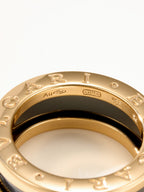 Close-up of gold-tone ring with engraved letters over an inner black band