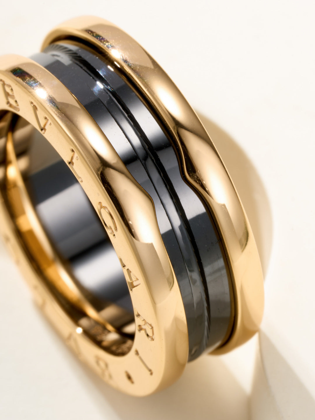 Close-up of gold-tone and black band ring with engraved outer edge