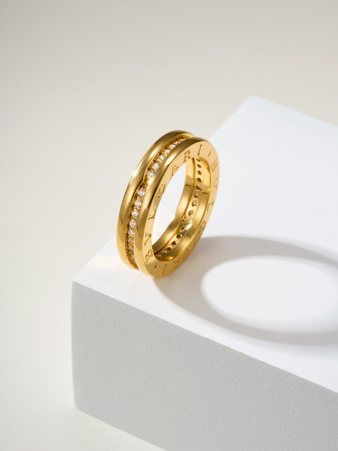 Gold ring with gemstone details and engraved markings, standing on a pedestal