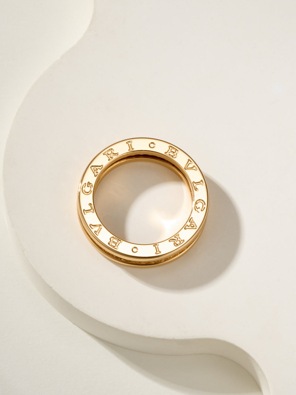 Gold circular ring with letter-like engraved details around the outer edge