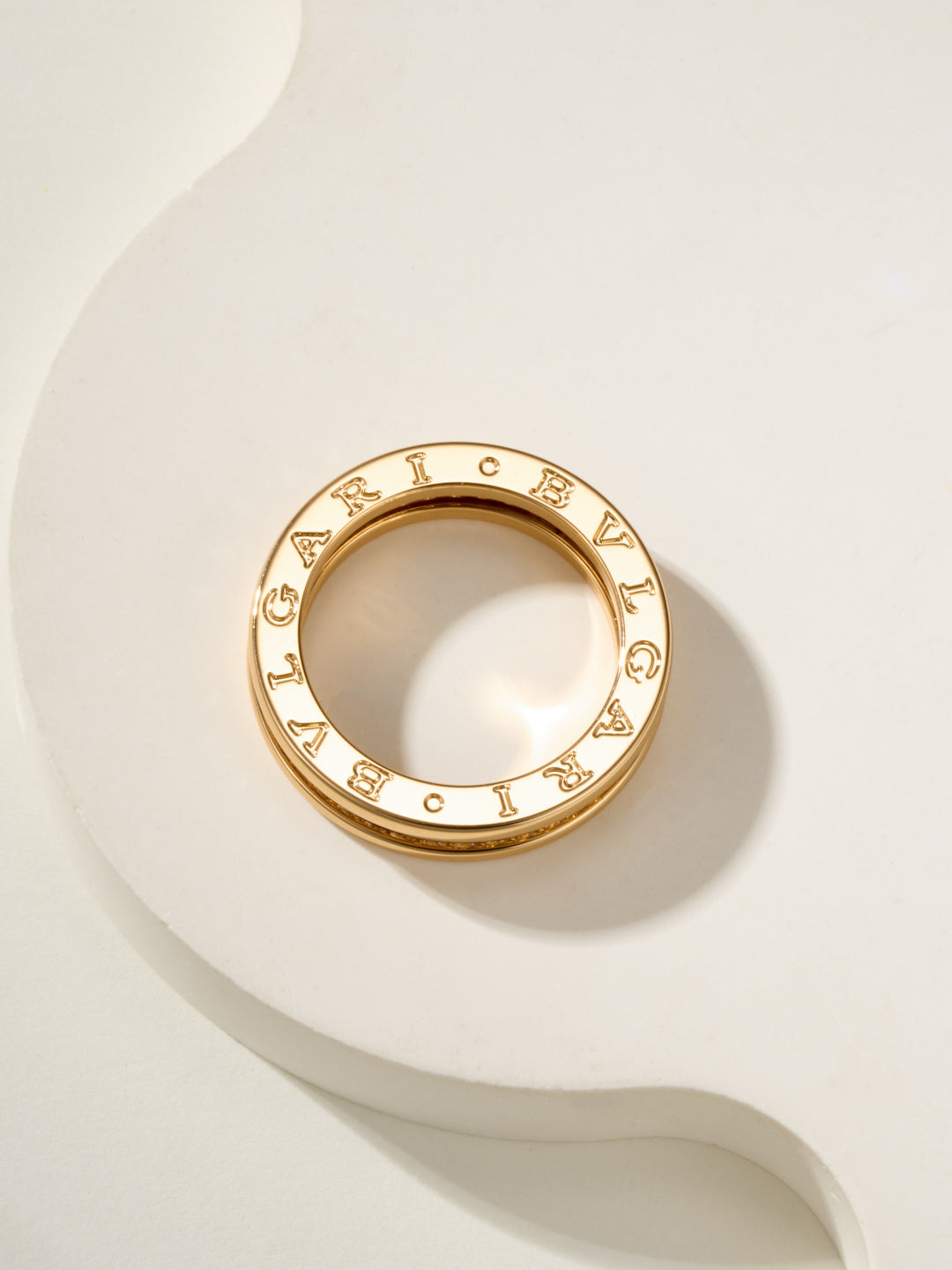 Gold circular ring with letter-like engraved details around the outer edge