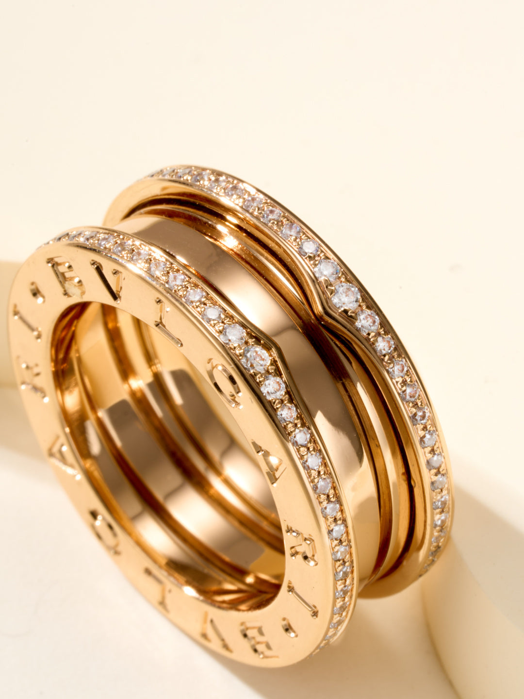 Close-up of stacked gold rings with diamond pavé rims and engraved inner band