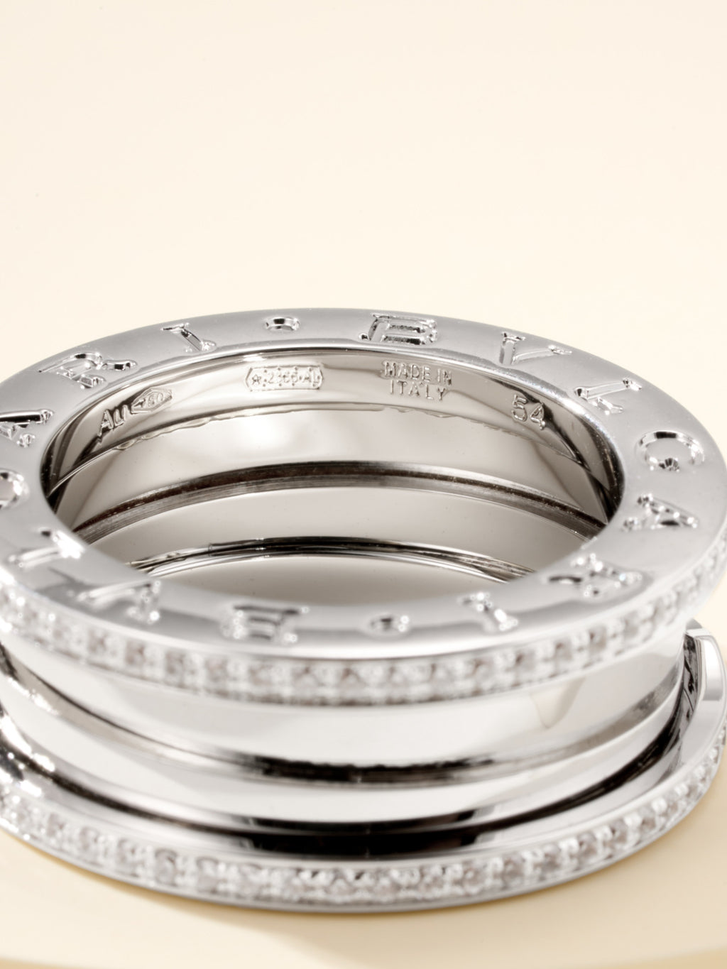 Close-up of stacked silver rings with diamond pavé rims and engraved inner band