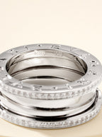 Close-up of stacked silver rings with diamond pavé rims and engraved inner band
