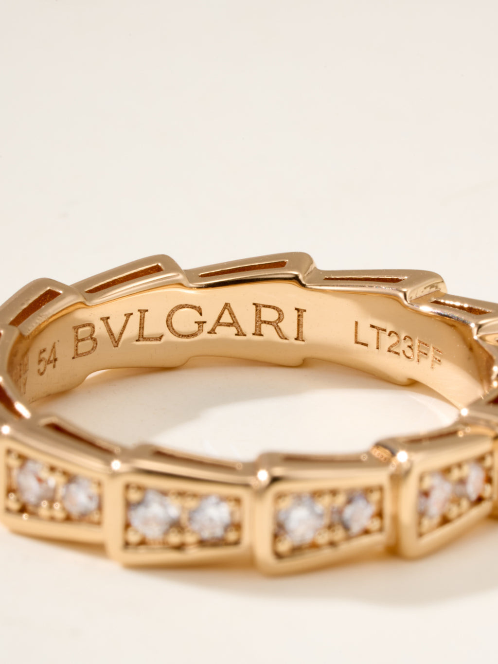 Gold bangle interior engraving with “BVLGARI” and bezel-set square stones.