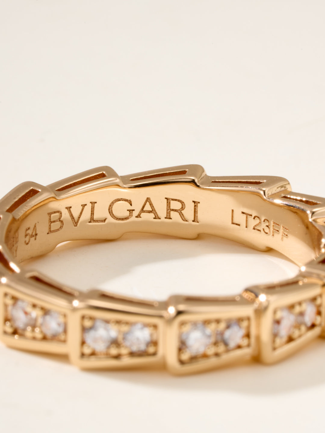 Gold bangle interior engraving with “BVLGARI” and bezel-set square stones.