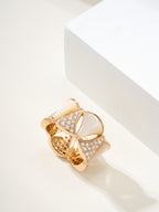 Bvlgari gold-tone ring with two white teardrop insets, pavé stones, and openwork texture.