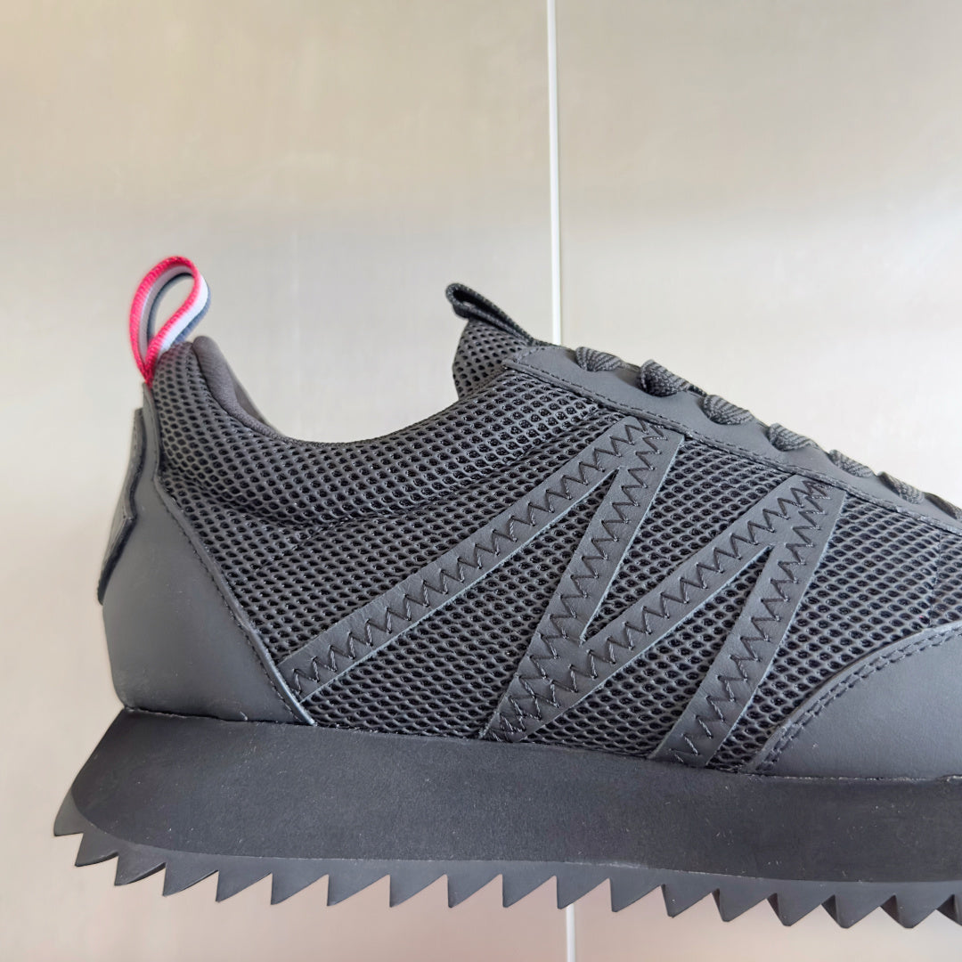 Moncler dark gray sneakers with mesh upper, diagonal stitch detail, and zigzag tread.