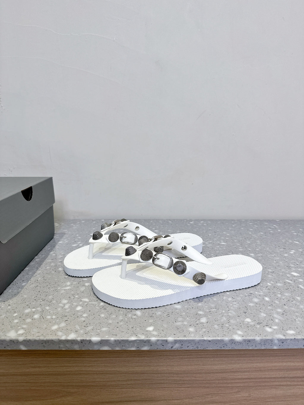 White thong sandals with studded oval hardware on the straps, side view pair.