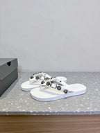 White thong sandals with studded oval hardware on the straps, side view pair.