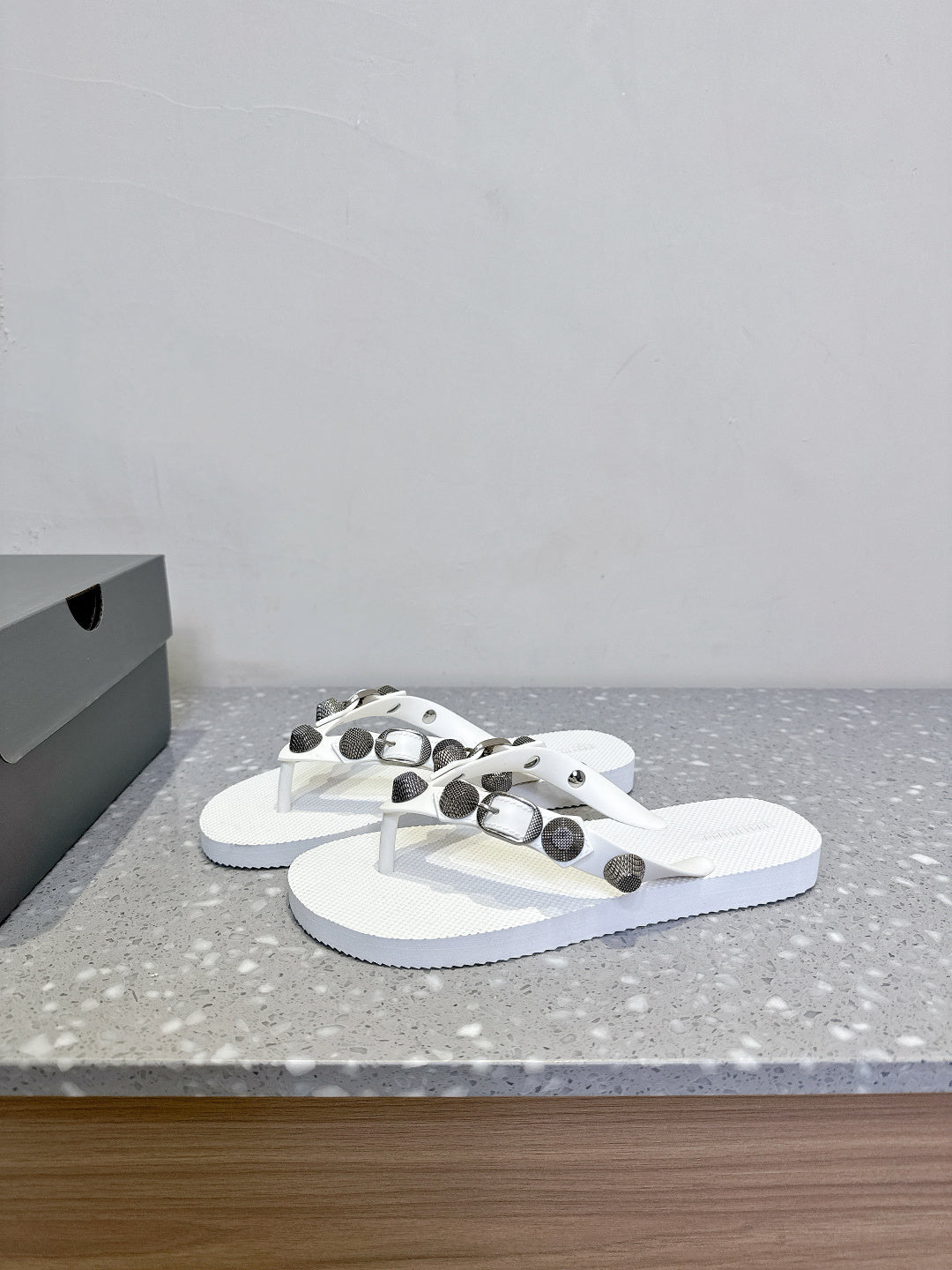 White thong sandals with studded oval hardware on the straps, side view pair.