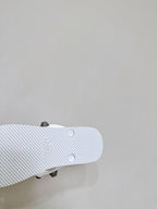 White sandal outsole close-up with tread pattern and small stud details underfoot.