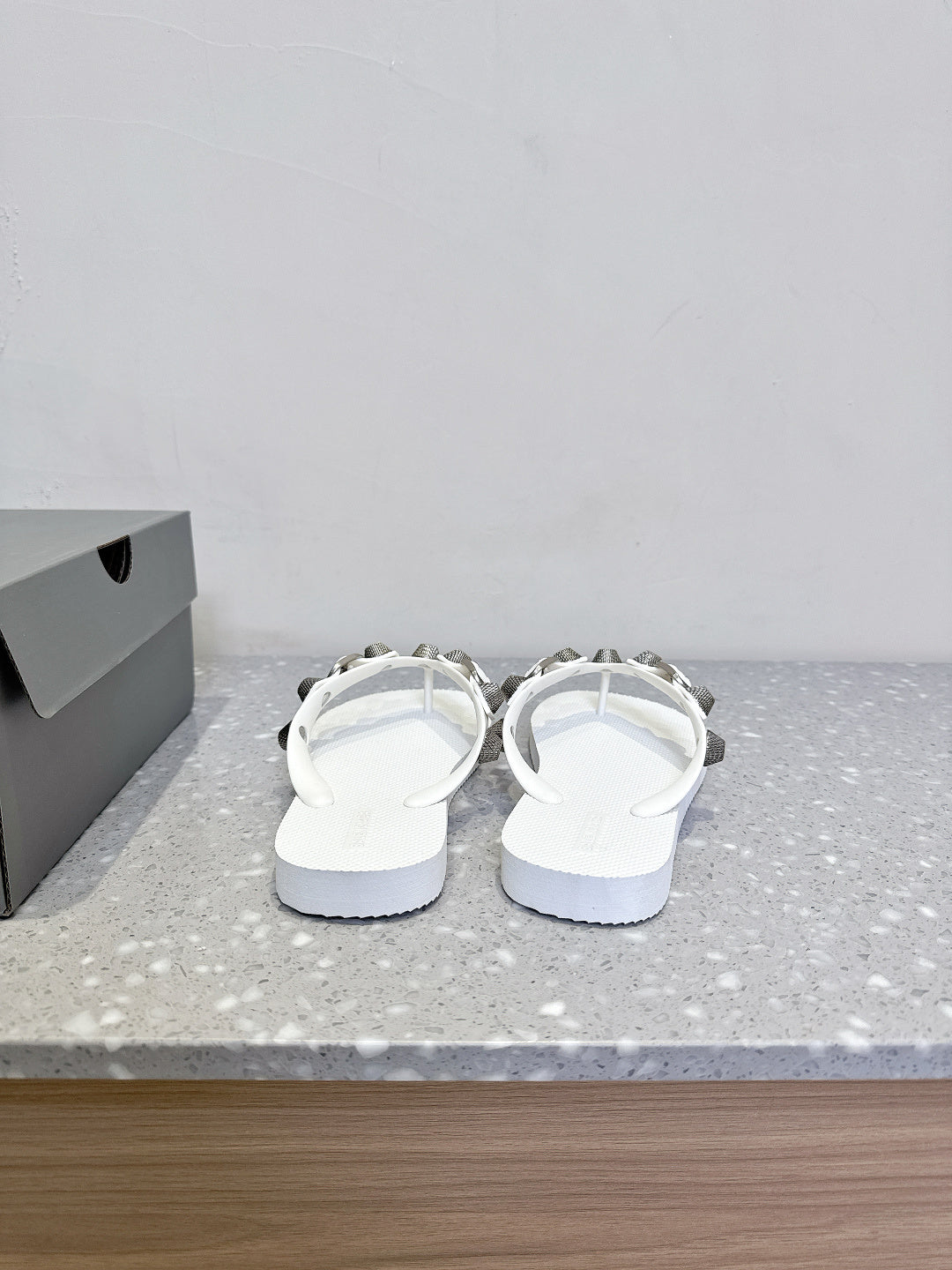 White thong sandals, heel-side view, studded strap detail with silver-toned hardware.