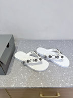 White thong sandals with studded strap hardware, angled side view of both shoes.