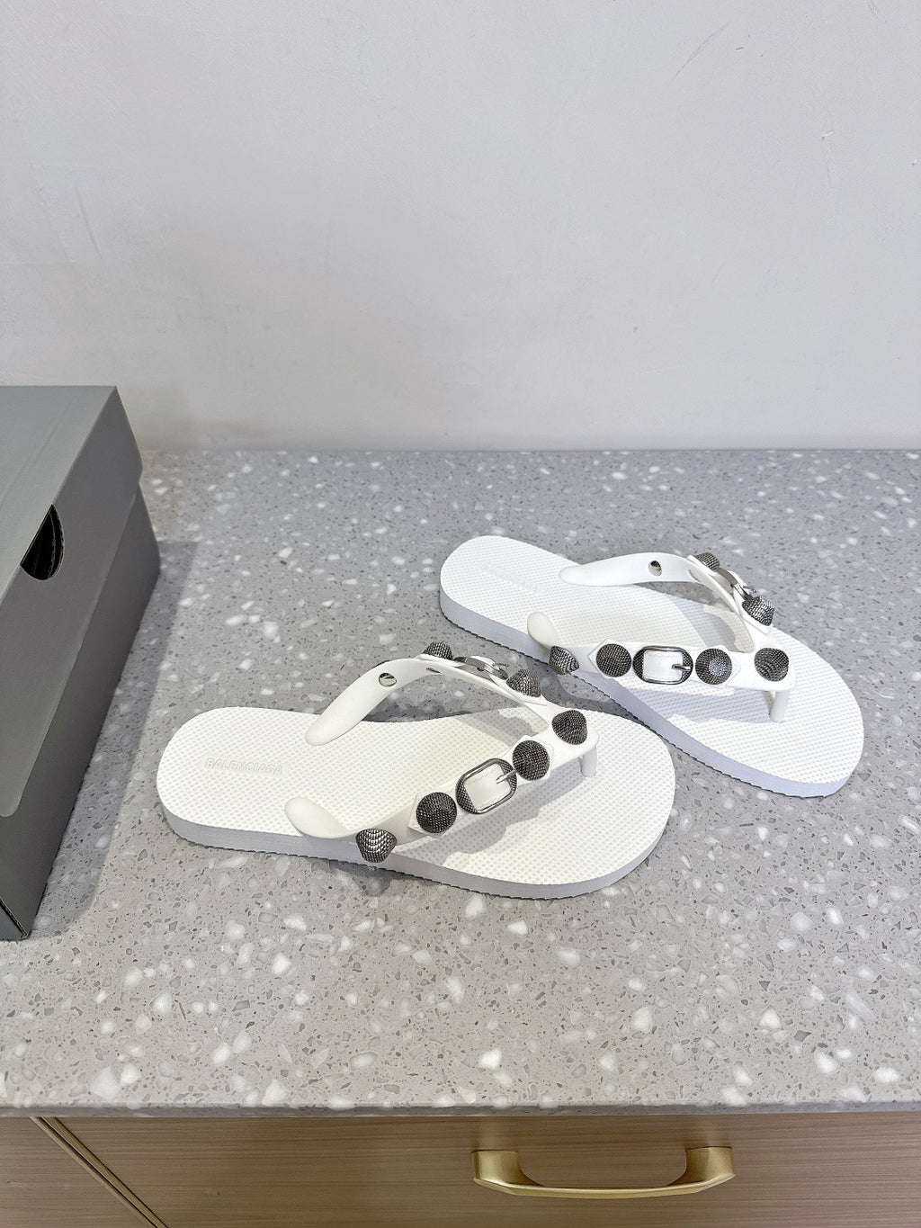 Pair of white thong sandals with studded strap accents and silver-toned hardware.