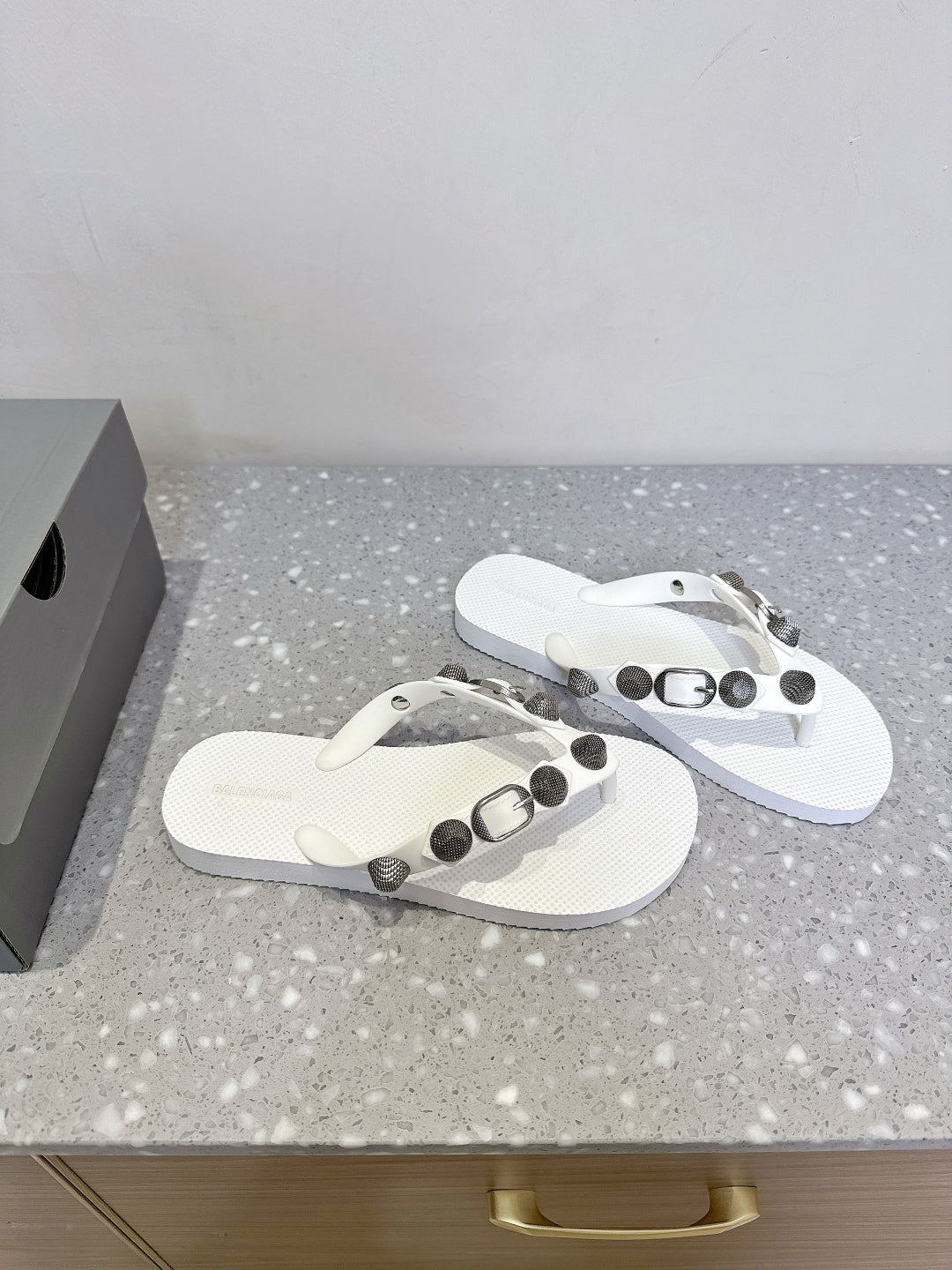 Pair of white thong sandals with studded strap accents and silver-toned hardware.