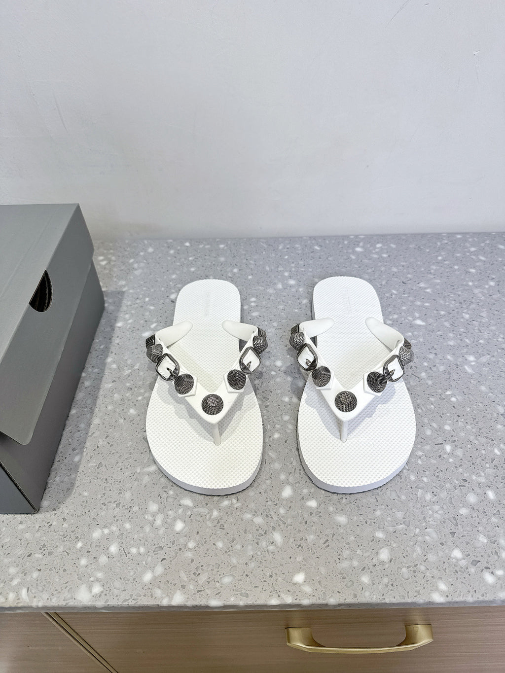 White thong sandals with studded oval hardware straps and cushioned footbeds.