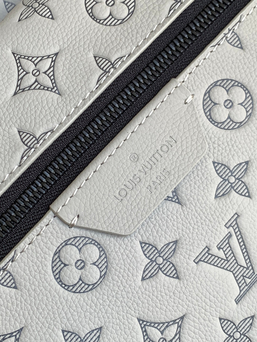 Louis Vuitton monogram leather bag with black zipper and light embossed pattern