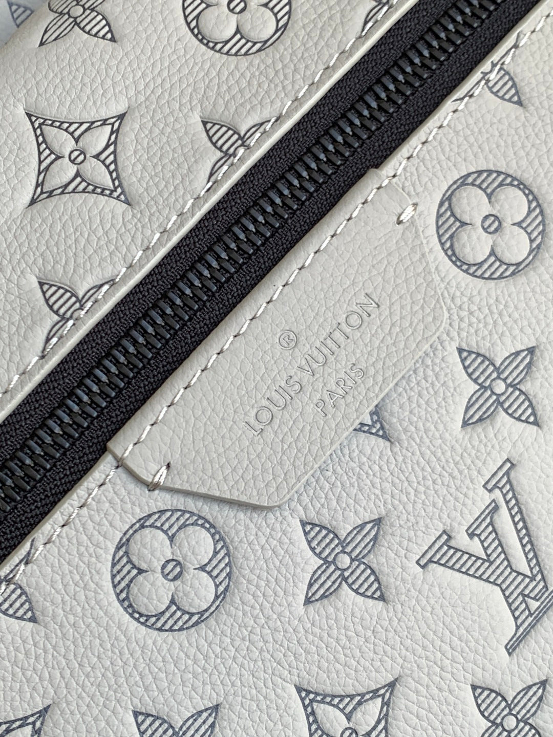 Louis Vuitton monogram leather bag with black zipper and light embossed pattern