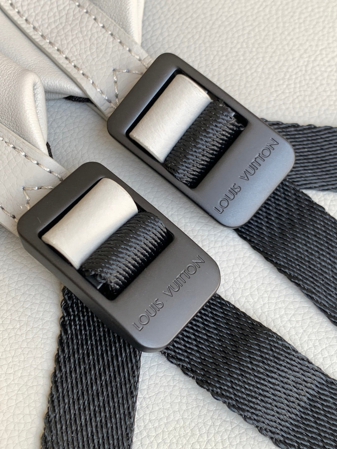 Louis Vuitton monogram bag with black webbing straps and gray buckle details