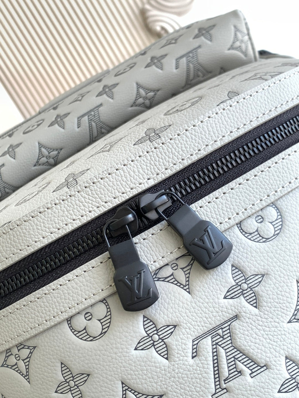 Louis Vuitton monogram leather bag with white trim stitching and black zipper tabs