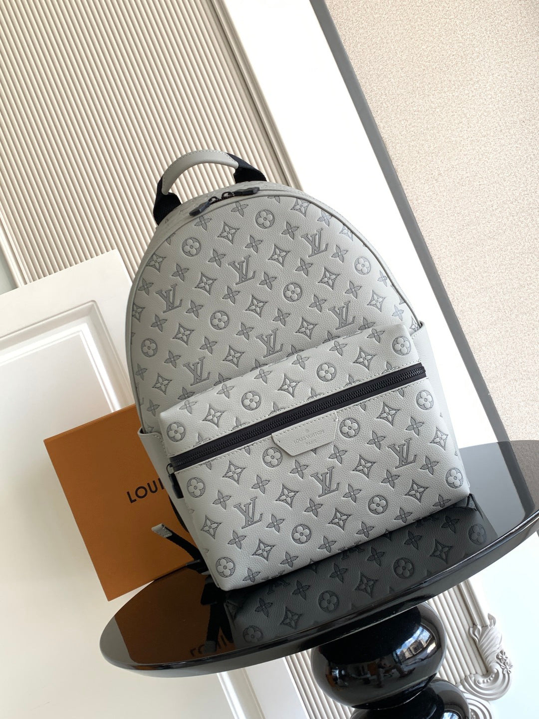 Louis Vuitton monogram bag with gray fabric, zip-top closure, and curved handles
