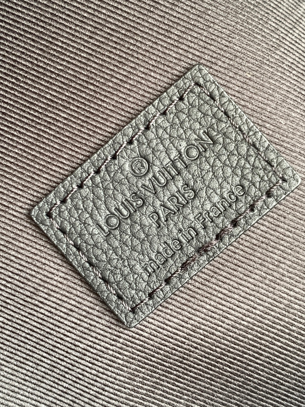 Louis Vuitton backpack leather tag with stamped logo text, close-up on fabric lining