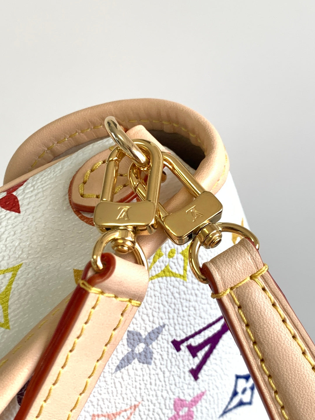 Gold-tone buckle hardware with beige strap and multicolor monogram trim.