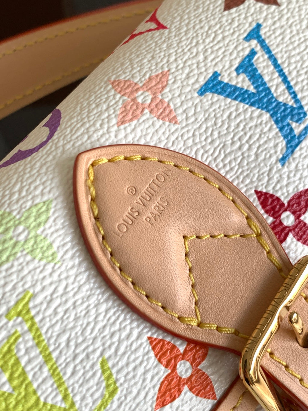 Beige leather strap end with Louis Vuitton embossing and multicolor stitching.