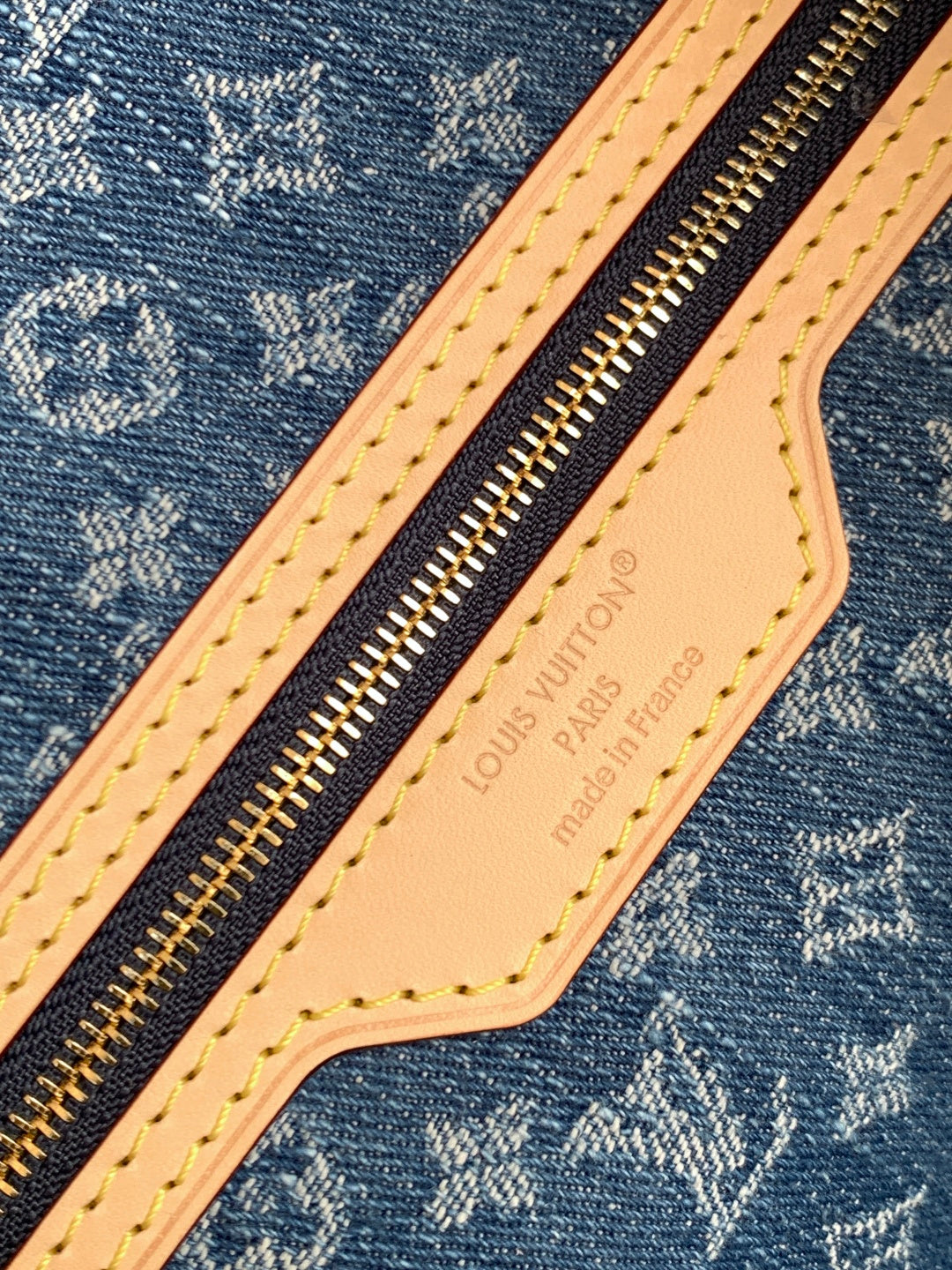 Blue monogram tote bag close-up: tan leather zip pull with Louis Vuitton imprint