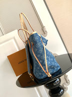 Blue monogram tote bag with tan shoulder strap and gold-tone clasp