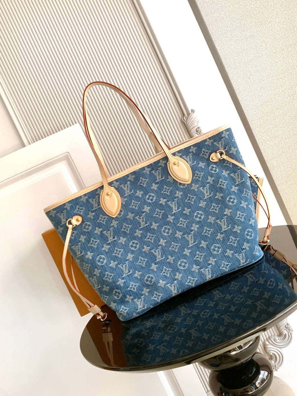Blue monogram tote bag with tan top handles, side straps, and gold hardware