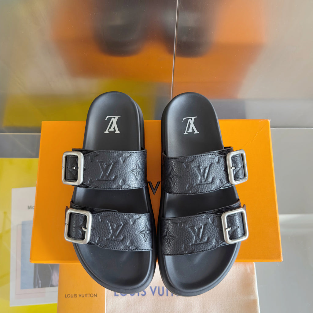 Two black Louis Vuitton slide sandals with embossed monogram straps and silver-tone buckles.