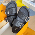 Black Louis Vuitton slide sandals with embossed logo straps and silver buckle fasteners.