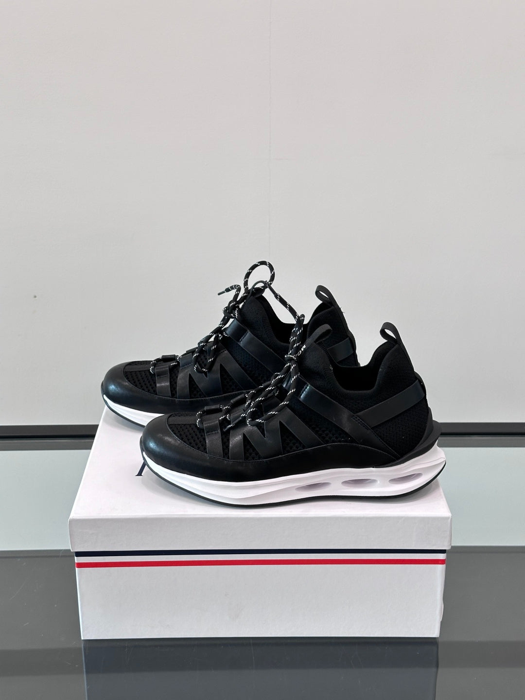 Black Moncler lace-up sneaker with textured upper, strap details, and white contrast sole.
