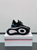 Black Moncler sneaker outsole view on box, with circular tread pattern and laces.