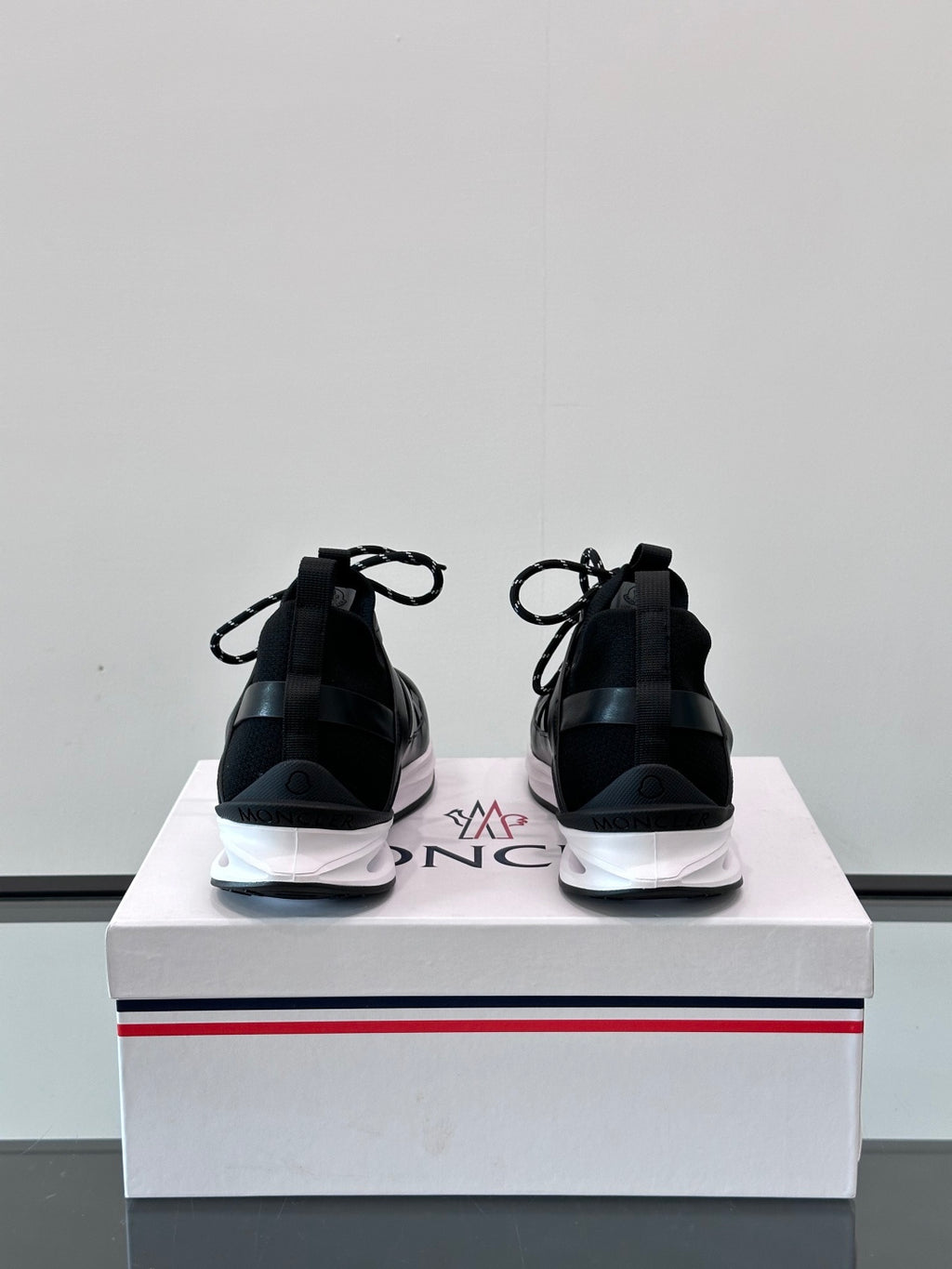 Black Moncler sneakers from back, showing heel tabs and white midsole edging.