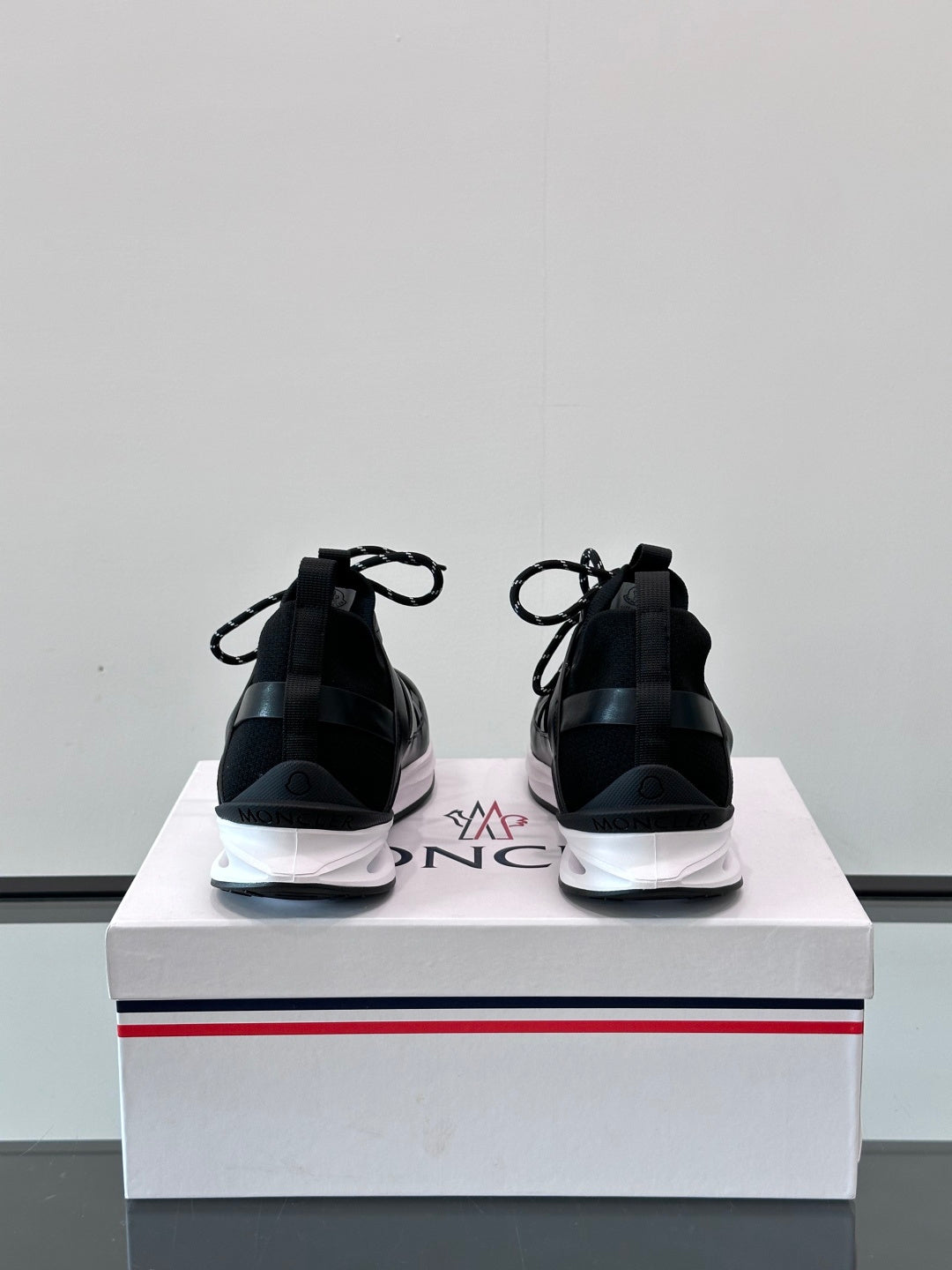 Black Moncler sneakers from back, showing heel tabs and white midsole edging.