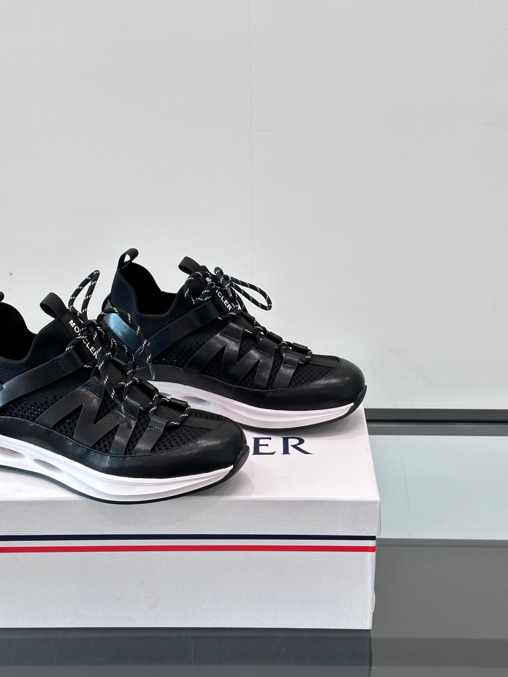Two black Moncler sneakers side-by-side, lace-up design with sporty strap overlays.