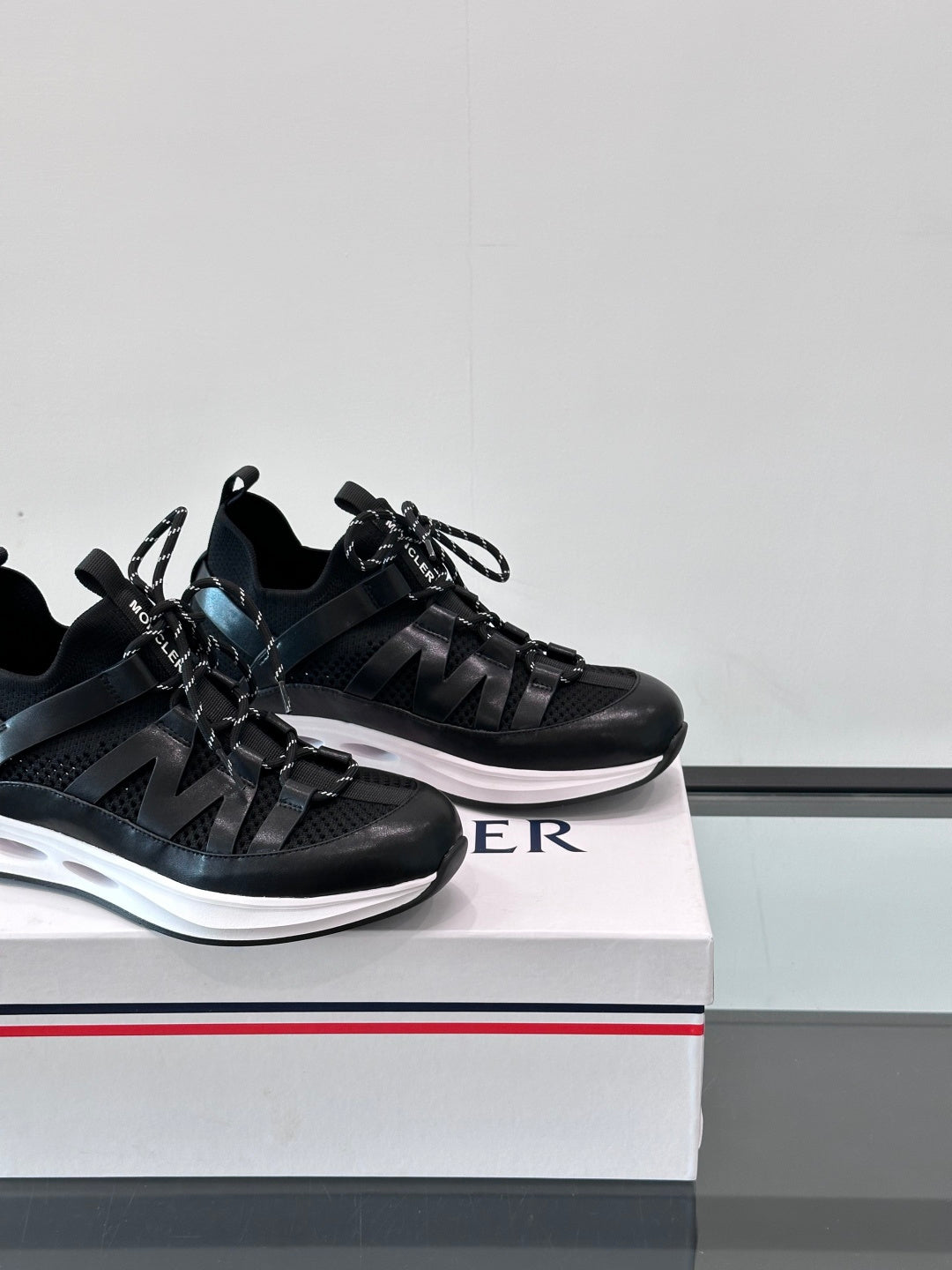 Two black Moncler sneakers side-by-side, lace-up design with sporty strap overlays.